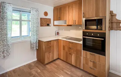 a kitchen with wooden cabinets and a window at Stunning Home In Vallavik With Wifi in Djønno