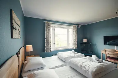 two beds in a blue room with a window at Gålå Høgfjellshotell in Gålå