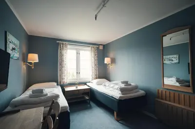 a blue room with two beds and a mirror at Gålå Høgfjellshotell in Gålå