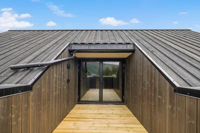 a wooden building with a roof with a door at Mountain View Apartment - penthouse in Stranda