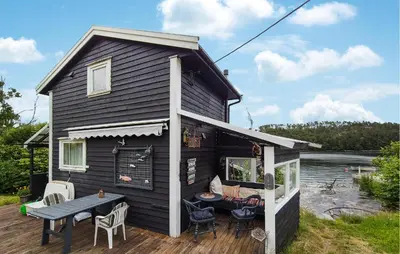 a black house with a table and chairs on a deck at Stunning Home In Førde I Hordaland in Erve
