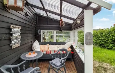 a screened in porch with a couch and a table and chairs at Stunning Home In Førde I Hordaland in Erve