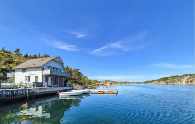a house on a dock with a boat in the water at Lovely Home In Urangsvåg in Steinsbø