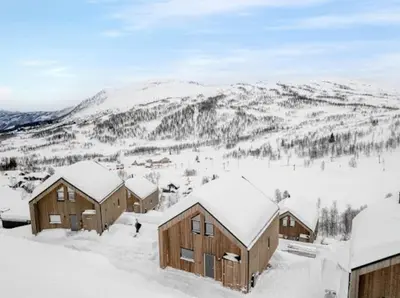 a group of buildings in the snow with mountains in the background at Flygende utsiktshytte med magisk utsikt in Sogndal