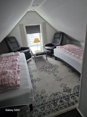 a attic room with two beds and chairs and a window at APARTAMENT Duże mieszkanie W centrum Ålesund in Ålesund