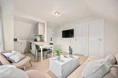 a white living room with a couch and a table at View to Bryggen - Renovated dec 24 - Historic cobblestone street in Bergen