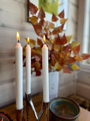 a group of white candles on a table with a plate at Cozy Ski-In Ski-Out Apartment on Geilo, Stunning Views! in Geilo