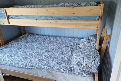 a bunk bed in a room with a wooden bunk bedutenewayangering at Koselig hytte på Austrheim