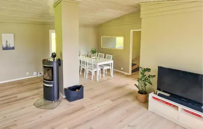 a living room with a large flat screen tv and a table at 4 Bedroom Awesome Home In Ølve in Ølve