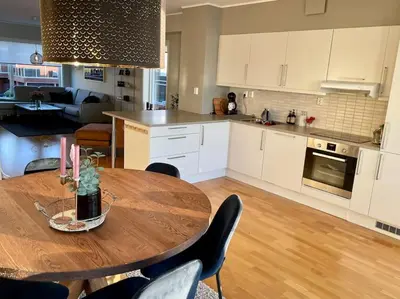 a kitchen and dining room with a wooden table with chairs at seaside house with stunning sunsets & sun all day Near Trondheim in Buvika