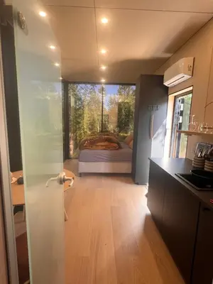 a room with a bed and a kitchen with a door at Speilsuite med egen badstue og panorama in Steinkjer