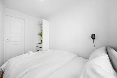 a white bedroom with two beds and a mirror at Homerentals Apartments - Behind Bryggen & historic cobblestone streets - 2 Floor renovated from february 2025 in Bergen