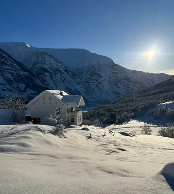 a house in the snow with mountains in the background at Jostedal Lodge in Jostedal