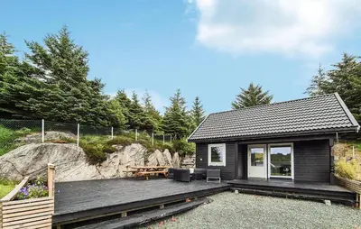 a cabin with a wooden deck and a picnic table at Amazing Home In Haugesund in Haugesund