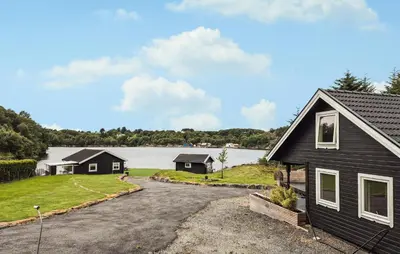 a black house with a driveway next to a lake at Amazing Home In Haugesund in Haugesund