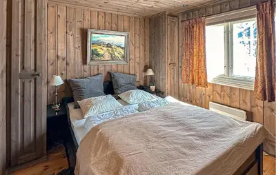 a bedroom with a large bed in a room with wooden walls at Stunning Home In Beitostølen With Sauna in Beitostøl