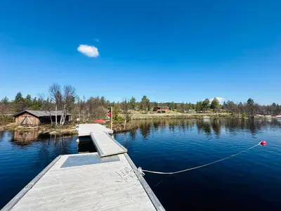 a dock on a lake with a house in the background at Nydelig naturperle på Nesbyen, nær Langedrag in Nesbyen