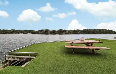 a picnic table sitting on the grass next to the water at 2 Bedroom Lovely Home In Haugesund in Haugesund