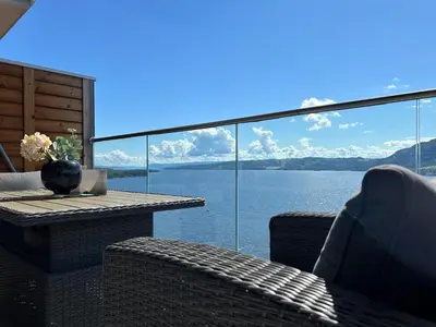 a balcony with a table and chairs and a view of the water at MJOS TOWER - Balcony Suite with lake view in Ringsaker