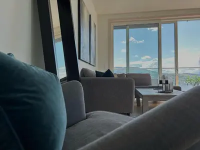 a living room with couches and a table and windows at MJOS TOWER - Balcony Suite with lake view in Ringsaker