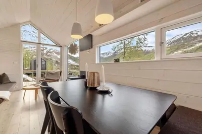 a dining room with a table and chairs and windows at Tiny Mountain Cabin I in Stranda