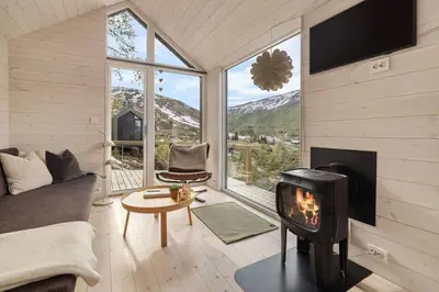 a living room with a fireplace and a stove at Tiny Mountain Cabin I in Stranda