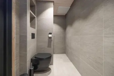 a bathroom with a black toilet and a wall at Mountain View Apartment - 102 in Stranda