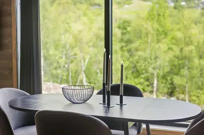 a table with three candles on it in front of a window at Mountain View Apartment - 102 in Stranda