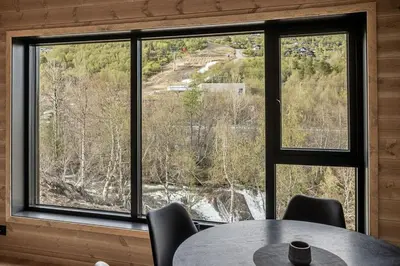 a table and chairs in a room with a large window at Mountain View Apartment - 205 in Stranda