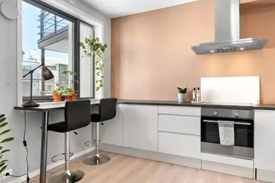 a kitchen with white cabinets and a black counter top at Sentral leilighet i Brosundet in Ålesund