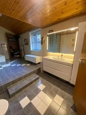 a bathroom with a tub and a sink and a mirror at Hus med plass til 7 personer til leie in Veka