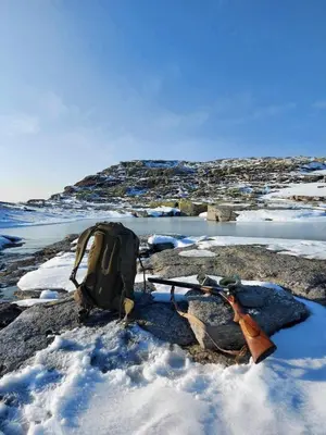 a backpack and skis on a rock in the snow at Handeland Lodge I Arctic Dome in Sauda