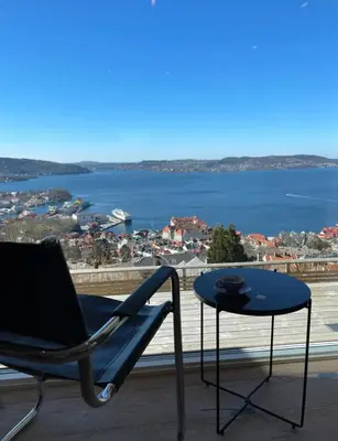 a chair and a table with a view of the water at Unique apartment with fantastic views in Bergen