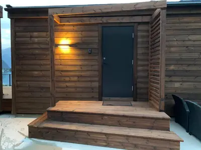 a wooden sauna with a black door on a deck at Stryn Golden Resort - Panorama II in Stryn