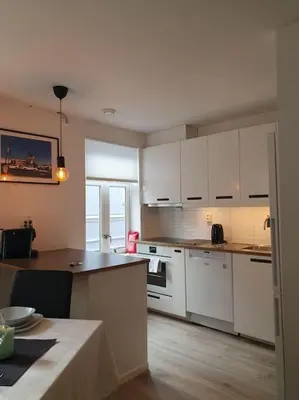 a kitchen with white cabinets and a table in it at Corner apartment with 2 bedrooms in the middle of the city centre in Trondheim