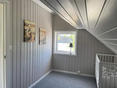 an attic room with a crib and a window at 6 person holiday home in BØMLO in Bømlo