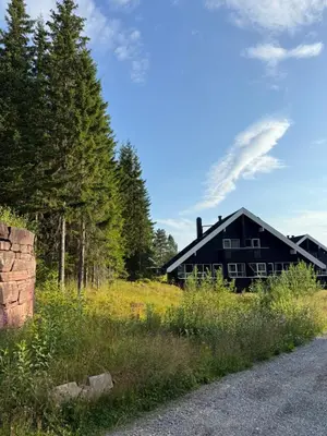 a black house sitting on a hill next to a road at Hytte med sentral beliggenhet in Trysil