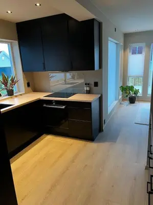 a kitchen with black cabinets and a wooden floor at Nytt hus i fredfullt nabolag in Verdal