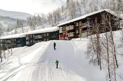 two people skiing down a snow covered slope in front of a lodge at Hemsedal, Ski in Ski out, Skarsnuten Panorama 55 in Tuv