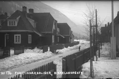 a person walking down a snow covered street with houses at Old Town House in Rjukan