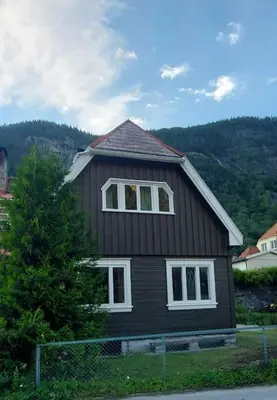 a black house with white windows and a tree at Old Town House in Rjukan