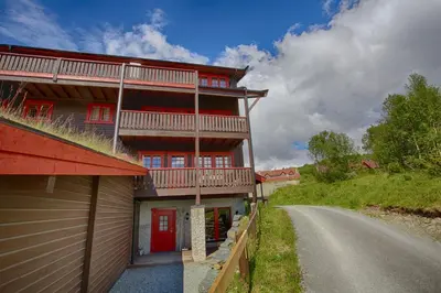 a large red building with red doors and a road at Ideal For Families And Groups Near Ski Slopes And Amenities in Beitostøl