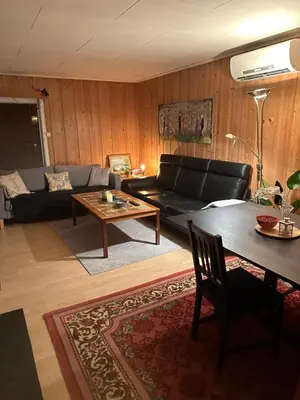 a living room with a black couch and a table at Trivelig leilighet med gratis parkering på stedet in Forset