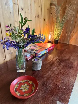 a table with a vase of flowers and books at Trivelig leilighet med gratis parkering på stedet in Forset