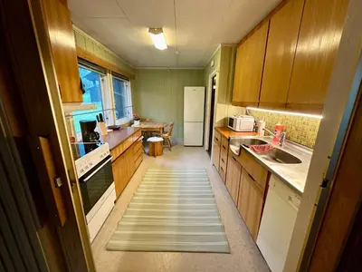 a kitchen with wooden cabinets and a stairway leading into a kitchen at Trivelig leilighet med gratis parkering på stedet in Forset