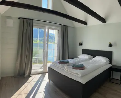 a bedroom with a large bed and a large window at Husslåttene apartments in Skei