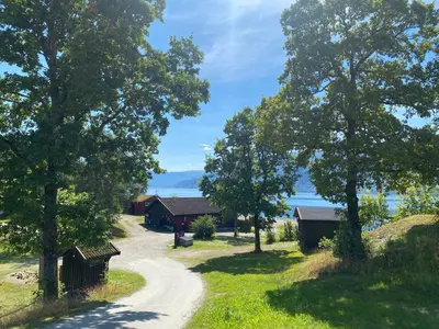 a dirt road leading to a cabin with trees at Veganeset Camping in Balestrand
