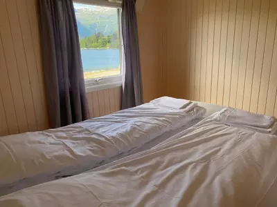 a bed in a room with a window at Veganeset Camping in Balestrand