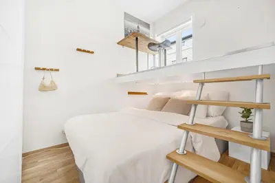 a small white bedroom with a bed and shelves at Sentral 2-romsleilighet in Trondheim