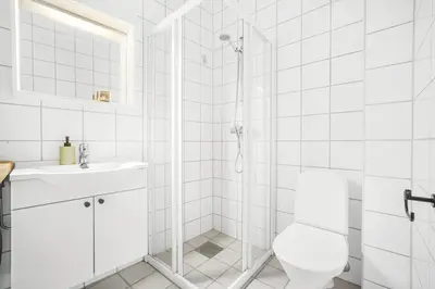 a bathroom with a shower with a toilet and a sink at Sentral 2-romsleilighet in Trondheim